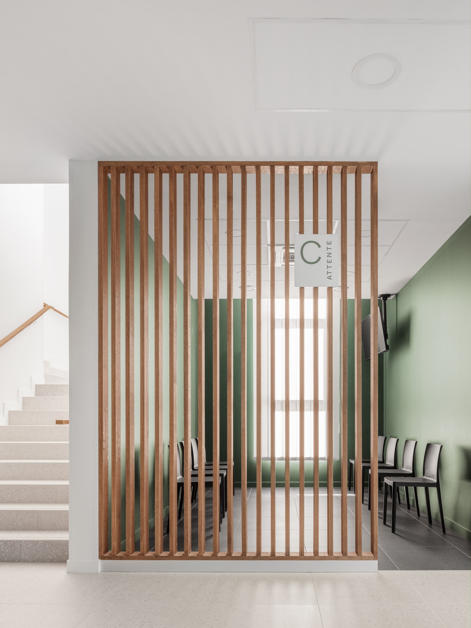 Salle d'attente : claustra bois et mur vert sauge